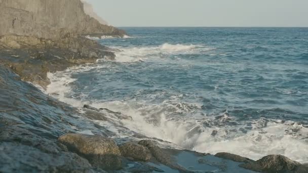 Óceán, kék víz hullámok összeomlik a vulkáni kőzetek. - Felvétel, videó