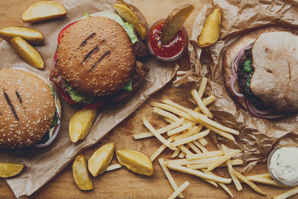 Fast food απομακρύνει το top view. Χάμπουργκερ, χοτ-ντογκ και τηγανιτές πατάτες - Φωτογραφία, εικόνα