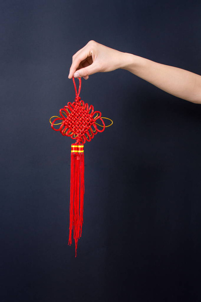 Mão segurando nó vermelho chinês
 - Foto, Imagem