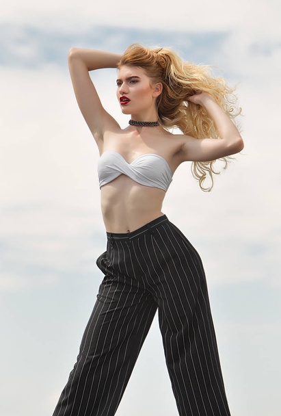 Model on the sky background. She is warming in top and striped p - Foto, imagen