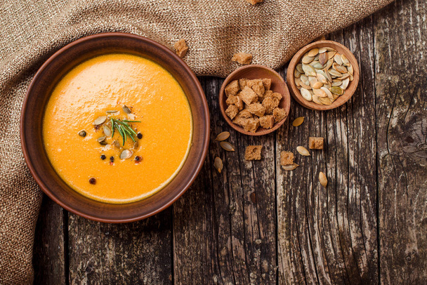 Bowl of pumpkin soup with bread crouton on dark wooden table. - Zdjęcie, obraz