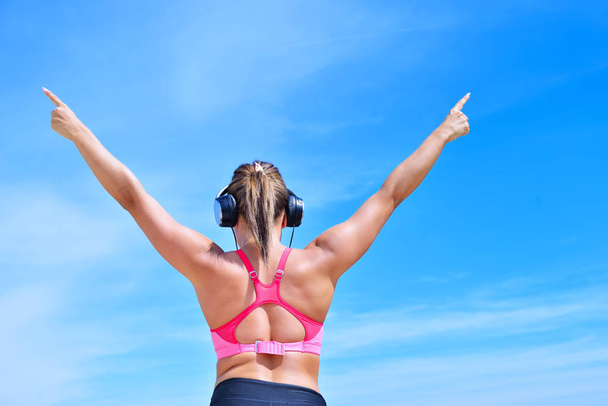Success fitness winning woman concept with earphones. - Foto, imagen