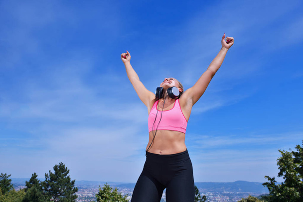 Success fitness winning woman concept with earphones. - Фото, изображение