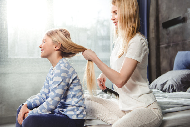 Mother combing hair of daughter  - Photo, Image