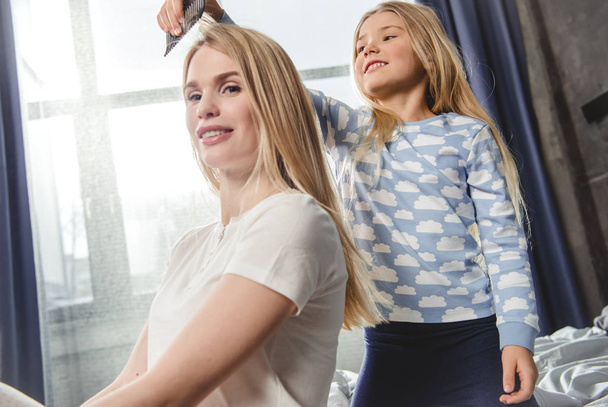 Daughter combing hair of mother - Foto, Imagen