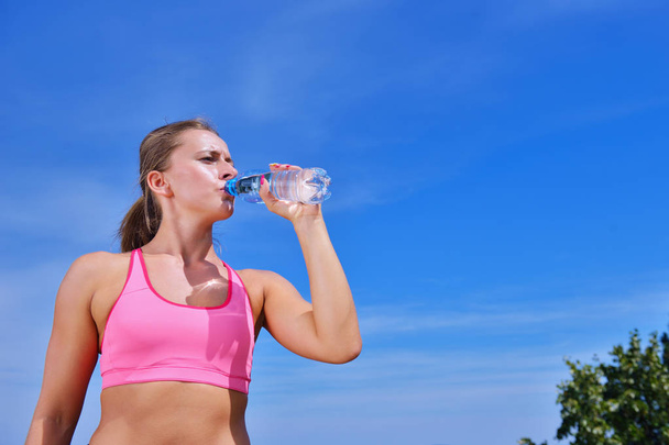 vrouw drinken water na joggen - Foto, afbeelding