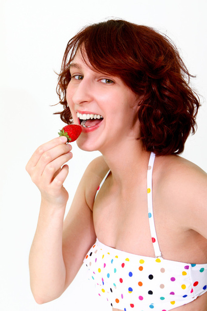 Young woman eating a strawberry - Фото, зображення