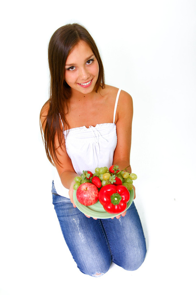Mujer joven con frutas y verduras en un plato
 - Foto, imagen