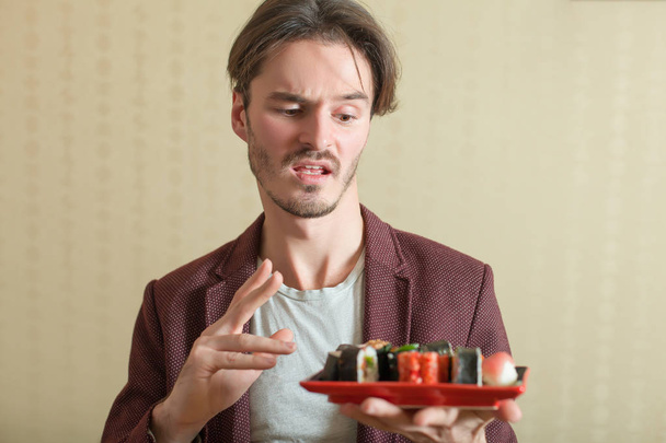 Young man eats sushi - Fotó, kép