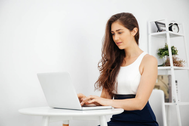 Beautiful Caucasian woman working on laptop on white desk over white isolated background with copy space - Photo, Image