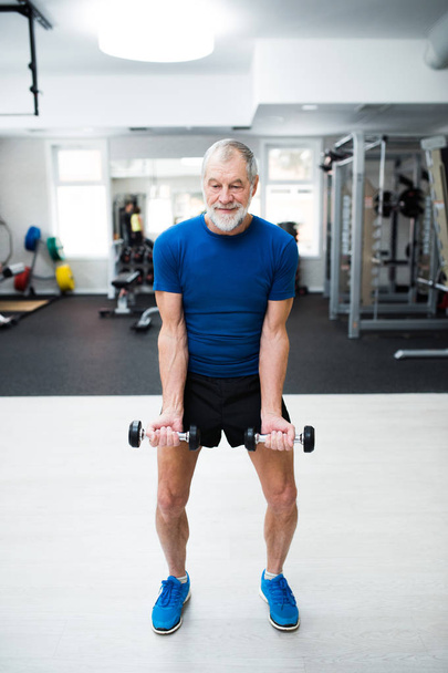 Senior man in gym working out with weights. - Фото, зображення