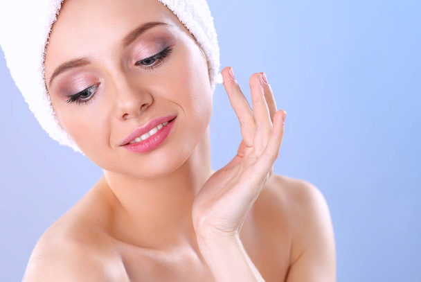 Beautiful young woman applying a creme her face isolated on gray background - Photo, image