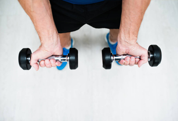 Hands of senior man in gym working out with weights - 写真・画像