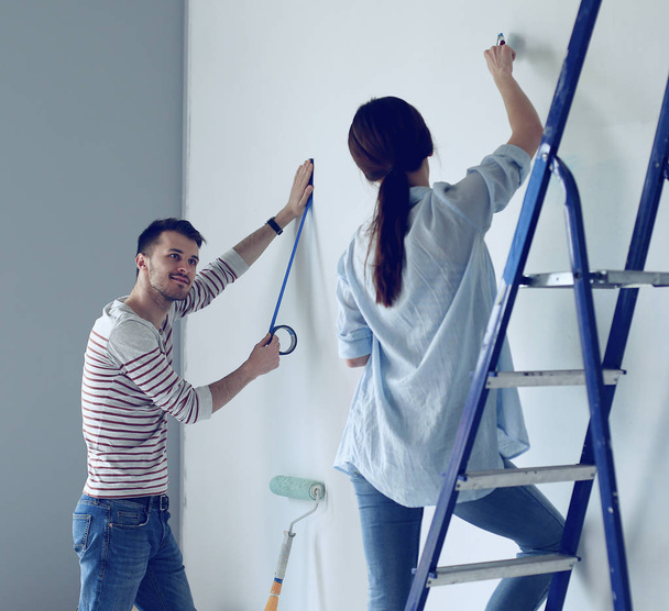 Portrait of happy smiling young couple painting interior wall new house - Photo, image