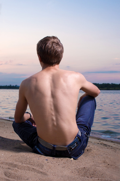 El tipo se sienta en la costa del río
 - Foto, Imagen