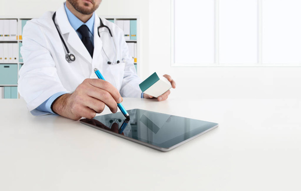 Arzt mit Tablet auf dem Schreibtisch verschreibt das Medikament - Foto, Bild