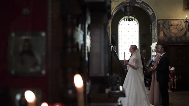 Наречений і наречена стояти зі свічкою в весільної церемонії в Православній церкві Nice Франції. Найкращий чоловік і фрейліна благословить перетину за нареченою. Православна Церква ритуальних традиції та звичаї - Кадри, відео