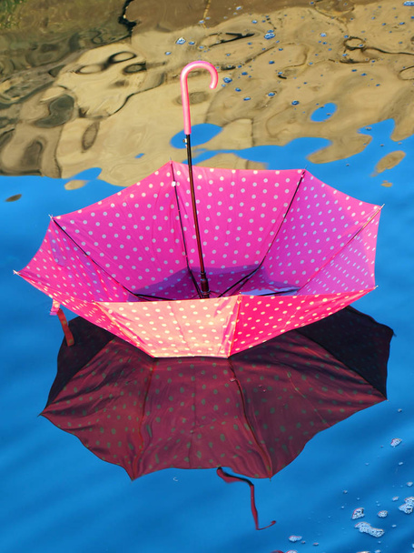 красный перевернутый зонтик, плавающий на поверхности воды
 - Фото, изображение