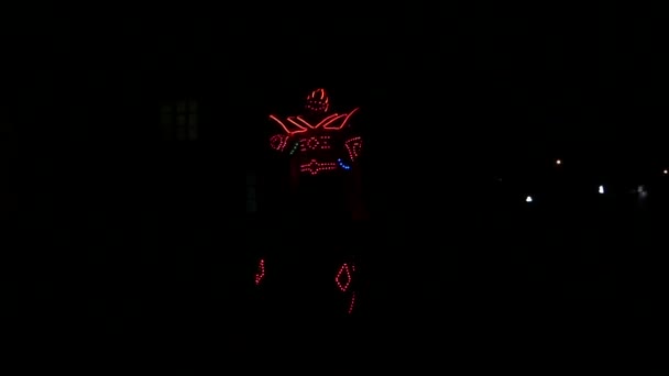 ein Clown im beleuchteten Kostüm auf Stelzen, der nachts tanzt - Filmmaterial, Video