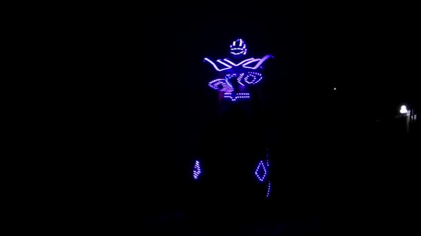 ein Clown in leuchtendem Kostüm auf Stelzen, der nachts tanzt. - Filmmaterial, Video