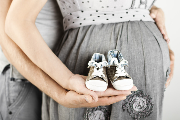 Newborn baby booties in parents hands. Close up. - Фото, изображение