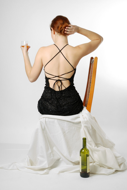 Young woman sitting with wineglass, rear view - Foto, Bild