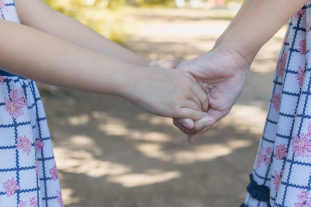 Επιλεκτική εστίαση μικρά παιδιά ζευγάρι πιασμένοι χέρι χέρι στο πάρκο. Έννοια ευτυχής παιδιά. - Φωτογραφία, εικόνα