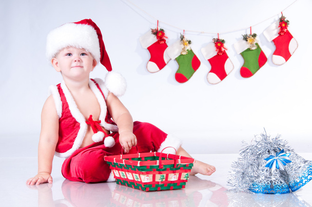 Cute baby Santa Claus with garlands and Christmas basket - Zdjęcie, obraz