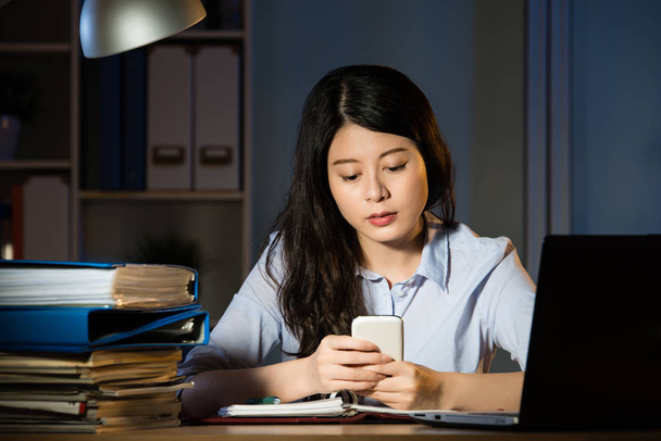 Aziatische zakelijke vrouw tekstbericht door smartphone overuren werken - Foto, afbeelding