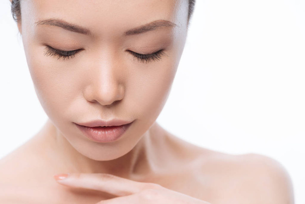 Gentle young Korean woman touching her skin in the studio - Zdjęcie, obraz