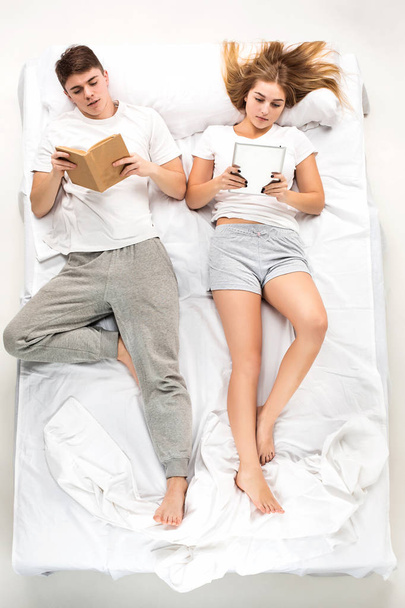The young lovely couple lying in a bed with books - Foto, Imagem