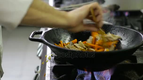 Chef-kok frituren groenten en vlees in een wok in de keuken - Video