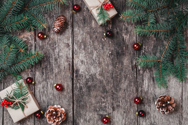 Sfondo natalizio con regalo di Natale, pigne, decorazioni rosse su sfondo in legno con rami di abete. Natale e Felice Anno Nuovo composizione. Posa piatta, vista dall'alto
 - Foto, immagini