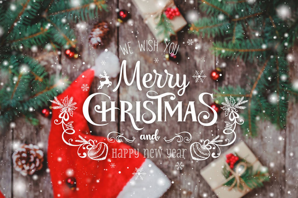 Boże Narodzenie skład z czerwony Santa hat, gałęzie jodły, szyszki, czerwone ozdoby, płatki śniegu na podłoże drewniane. Boże Narodzenie i nowy rok karty. Widok płaski świeckich, top - Zdjęcie, obraz