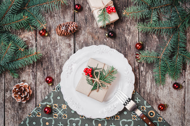 Plato de Navidad con regalo sobre fondo de vacaciones de madera con, conos de pino, decoraciones rojas, ramas de abeto. Navidad y Feliz Año Nuevo composición. Piso tendido, vista superior
 - Foto, imagen