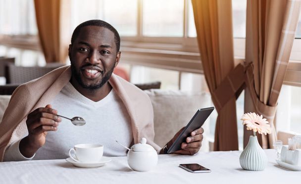Positive African American man enjoying his breakfast in the cafe - 写真・画像