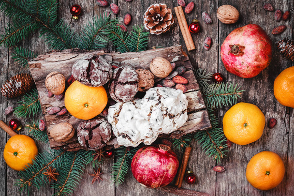 Різдвяна листівка. Різдвяні подарунки, шоколад печиво, гранат, мандарини, горіхи, какао-боби, ялиця гілки на дерев'яні snowy фону. Xmas та новим роком складу. Вид зверху, вибіркове фокус - Фото, зображення