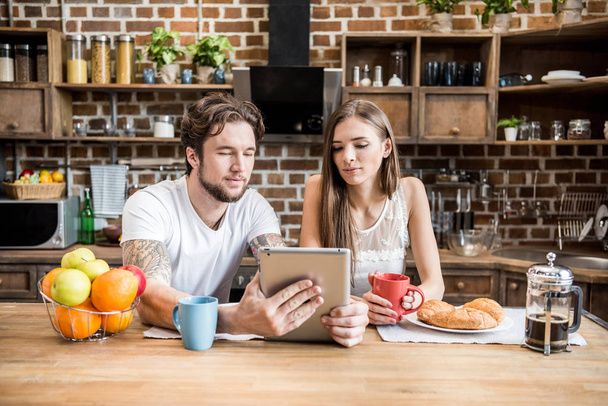 Couple using digital tablet at kitchen - Fotó, kép