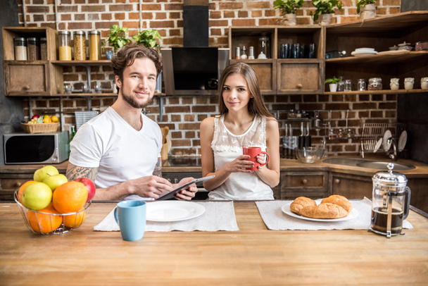 Couple using digital tablet at kitchen   - Фото, зображення