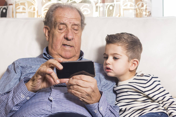 Opa und Enkel schauen aufs Smartphone - Foto, Bild
