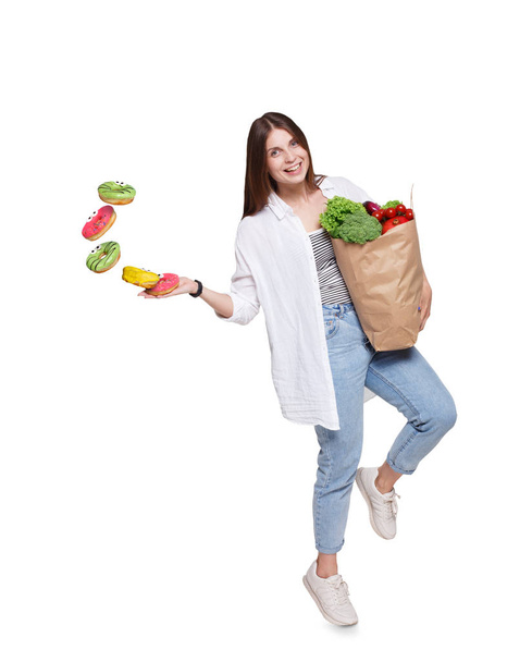 Ευτυχισμένη γυναίκα με υγιεινά τρόφιμα πετάτε ανθυγιεινά ντόνατς - Φωτογραφία, εικόνα