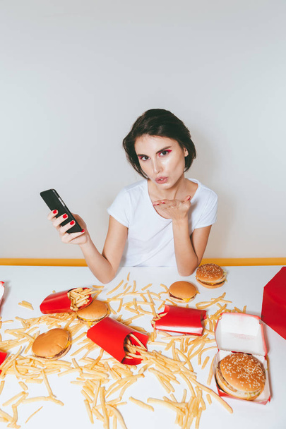 Woman sending kiss at the table with fast food - Valokuva, kuva