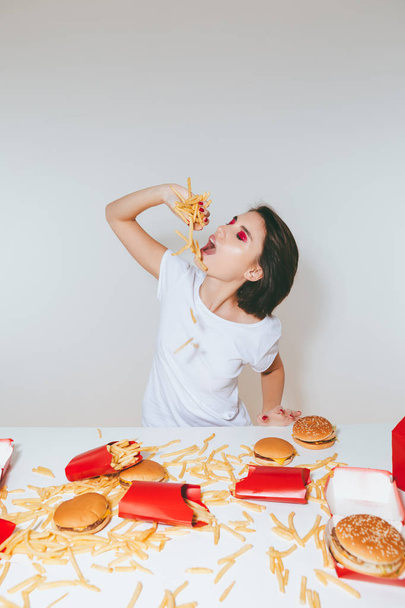 Woman eating french fries at the table with fast food - Фото, изображение