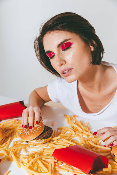 Attractive young woman sitting at the table with fast food - Foto, immagini