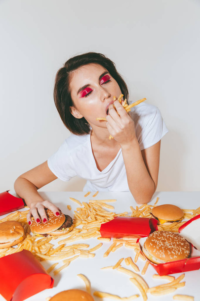 Pretty woman sitting at the table and eating french fries - 写真・画像