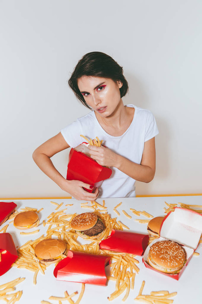 Charmante femme assise et mangeant des frites de la boîte rouge
 - Photo, image