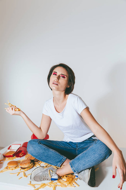 Woman sitting on the table and holding french fries - Foto, imagen