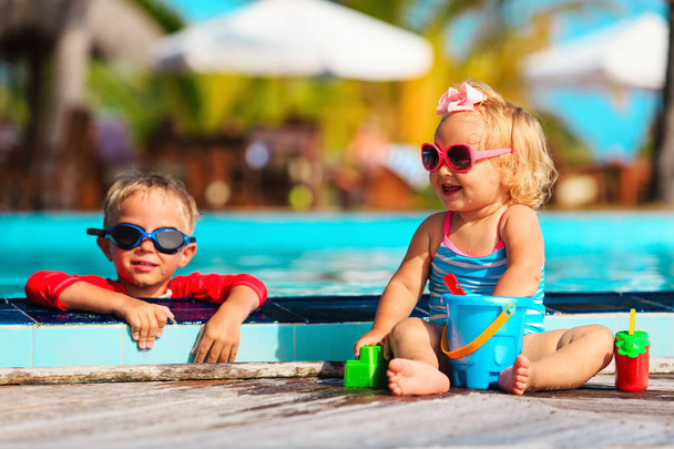 kleine jongen en meisje spelen in zwembad op strand - Foto, afbeelding
