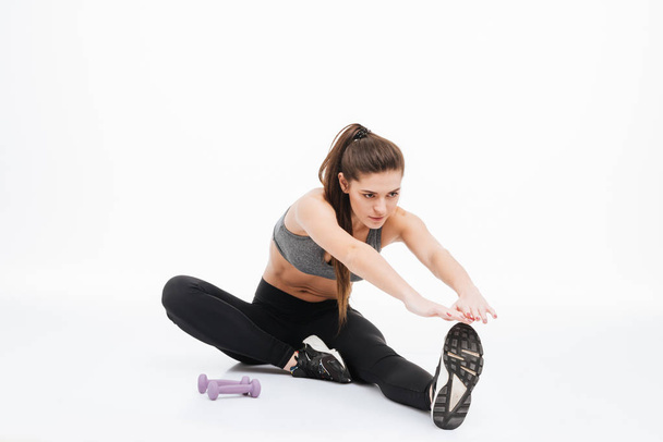 Portrait of happy sports woman stretching legs on the floor - Foto, Imagem