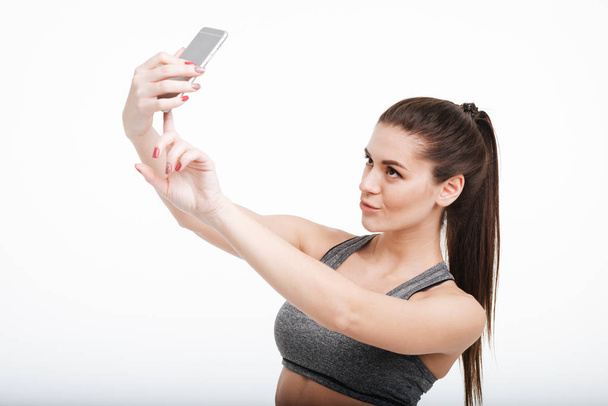 Pretty brunette sports woman taking selfie with her mobile phone - Photo, Image